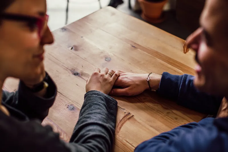 A couple holding hands listening to each other speak