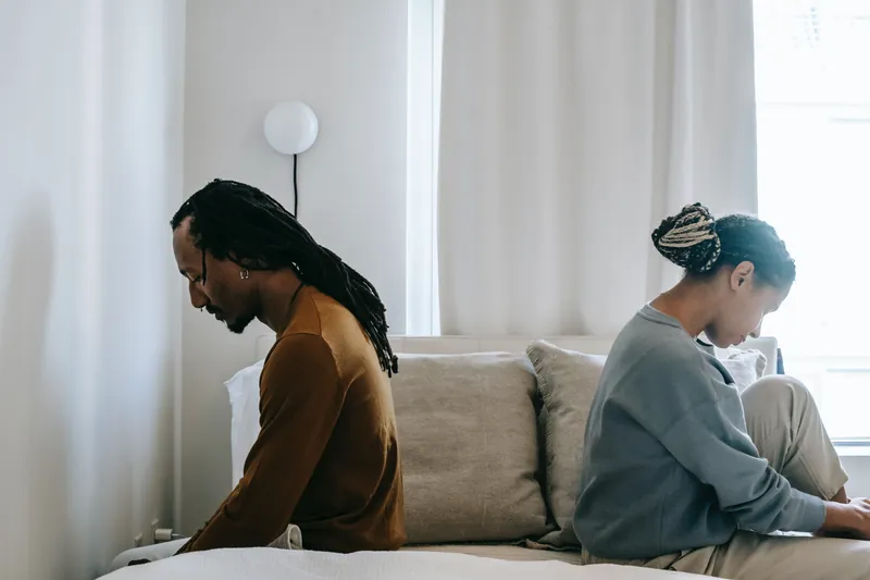 A couple sitting on a bed facing away from each other after a misunderstanding