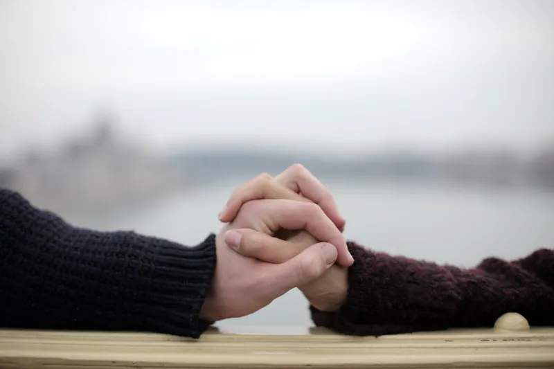 Arms stretched across a table with fingers clasped over each other