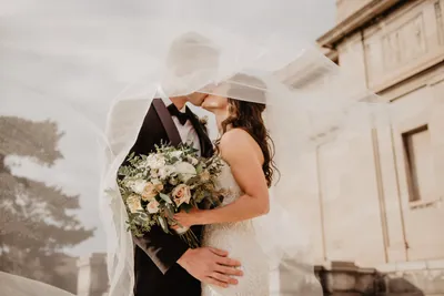 Bride and groom kissing underneath bridal veil