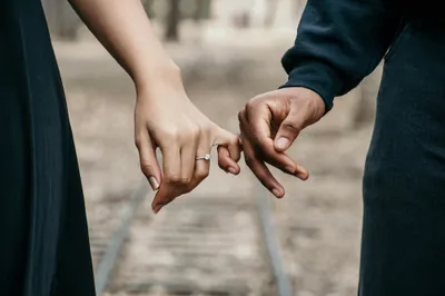 Interracial couple’s hands holding pinky fingers
