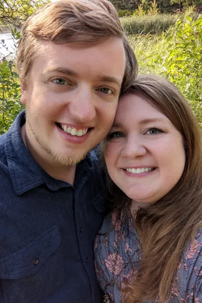 Jake and Melissa standing close together in front of a pond