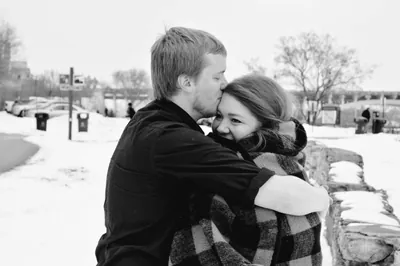 Jake kissing Melissa’s forehead on a bridge in the snow