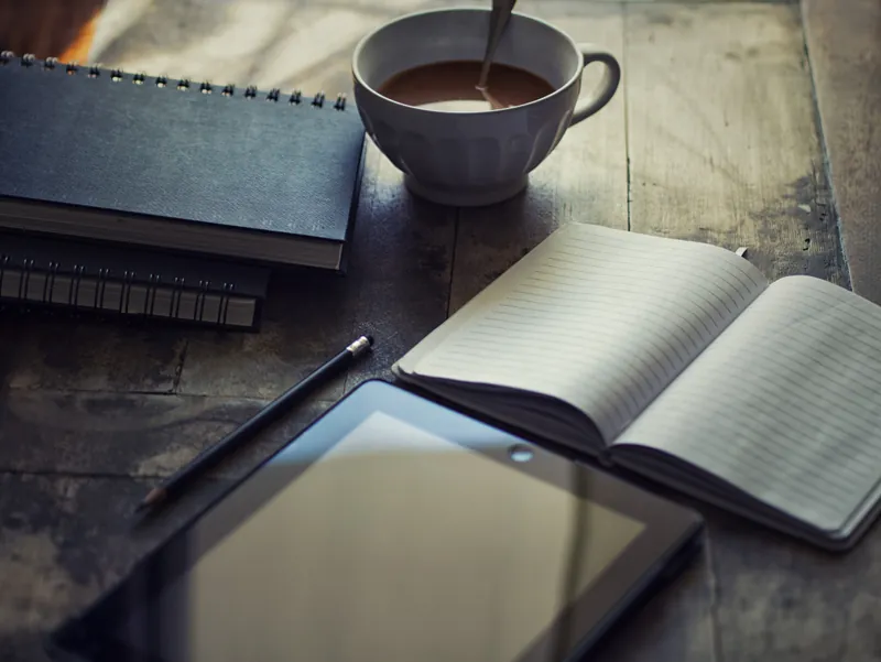 Tablet, coffee and journal sitting on table ready to use.