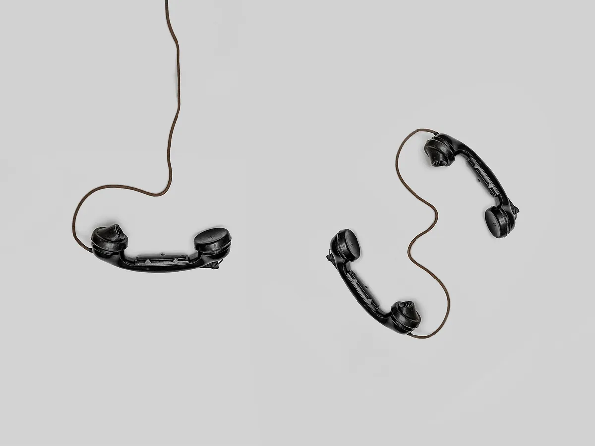 Two corded dial phones sitting on a white background