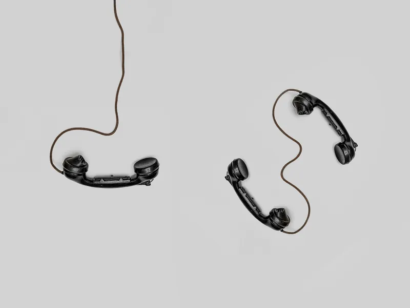 Two corded dial phones sitting on a white background