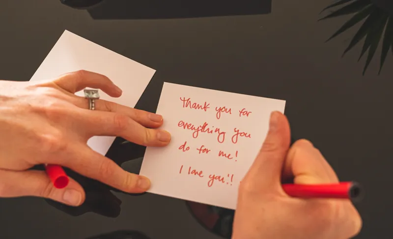 Writing a thank you note on a post it