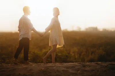 Man and woman holding hands walking at dusk